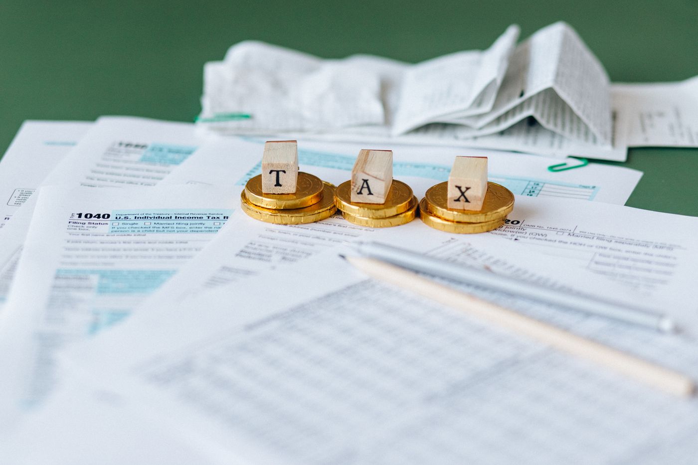 Invoice and tax paperwork spread across a desk beside a pen