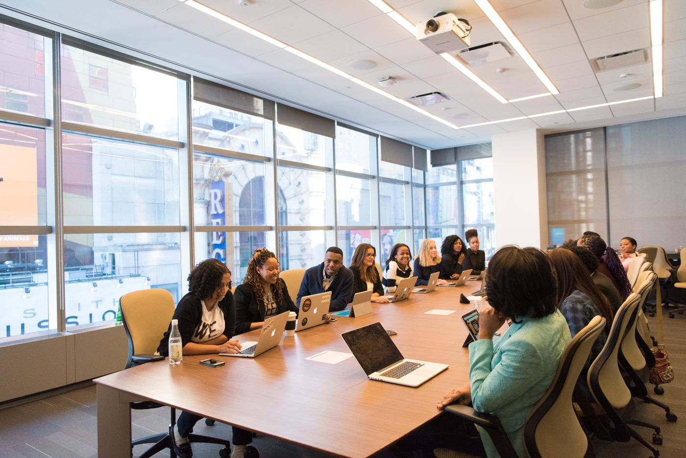 An empty meeting room with a long table, chairs and a wall-mounted display